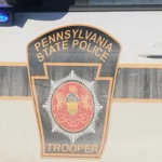 Police cruiser lights near a seized silver Honda Accord in a gold bar scam case