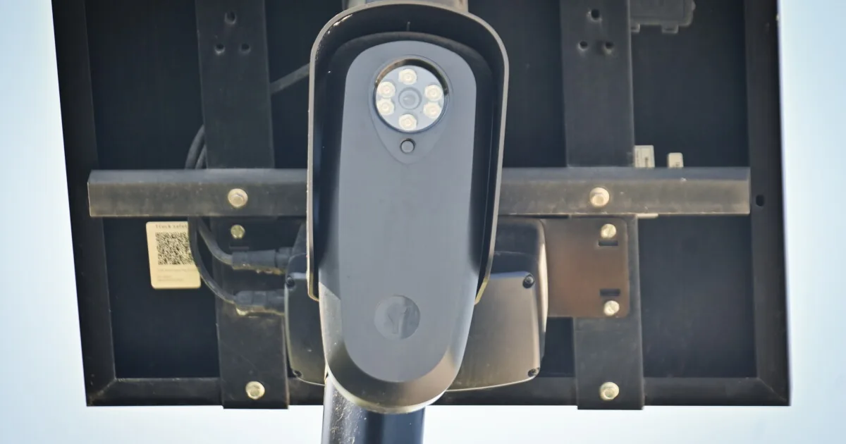 A license plate reader camera mounted on a pole beside a roadway